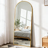 A full length oval mirror with a gold frame reflecting a bedroom and a window light.