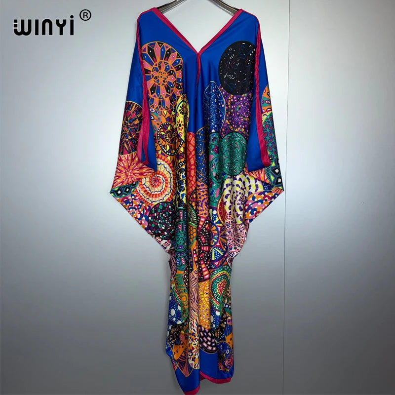 Leuchtend boho-blumiges Maxi-Kleid mit blau-, orange- und grünem Muster auf einem Hänger.