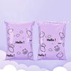 A pair of purple self-sealing mailing bags featuring a white outline of a happy bear in cloud shapes.