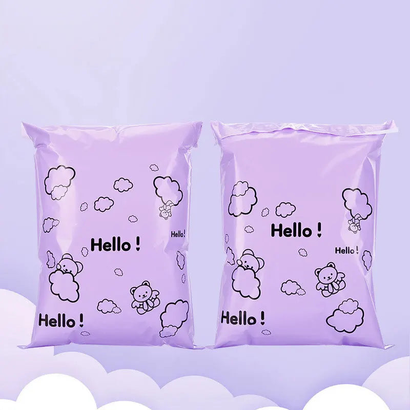 A pair of purple self-sealing mailing bags featuring a white outline of a happy bear in cloud shapes.