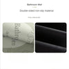 A pair of double-sided non-slip bath mats, one light beige and one black, shown rolled up.