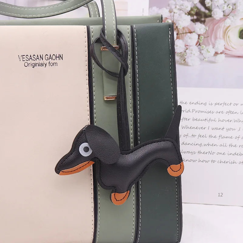 A dark green leather bag featuring a dachshund-shaped keychain charm.