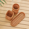 A set of seven handwoven natural wicker serving baskets resting on a light wooden surface.