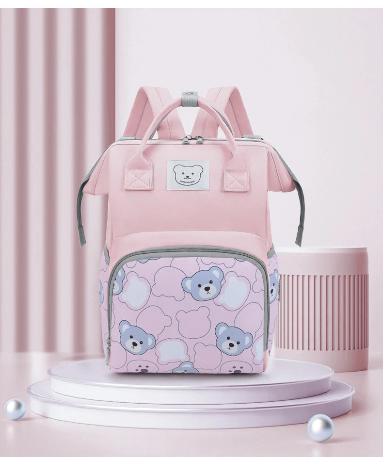A pink bear print waterproof diaper backpack displayed on a white stand.