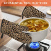 A pair of leopard print oven gloves resting on a stovetop with a bowl of soup in the background.