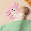 A baby is interacting with a pink palm-shaped sensory toy on a light background.