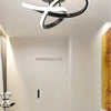 Modern clover LED ceiling light fixture with a black and white ring design mounted on a white wall.