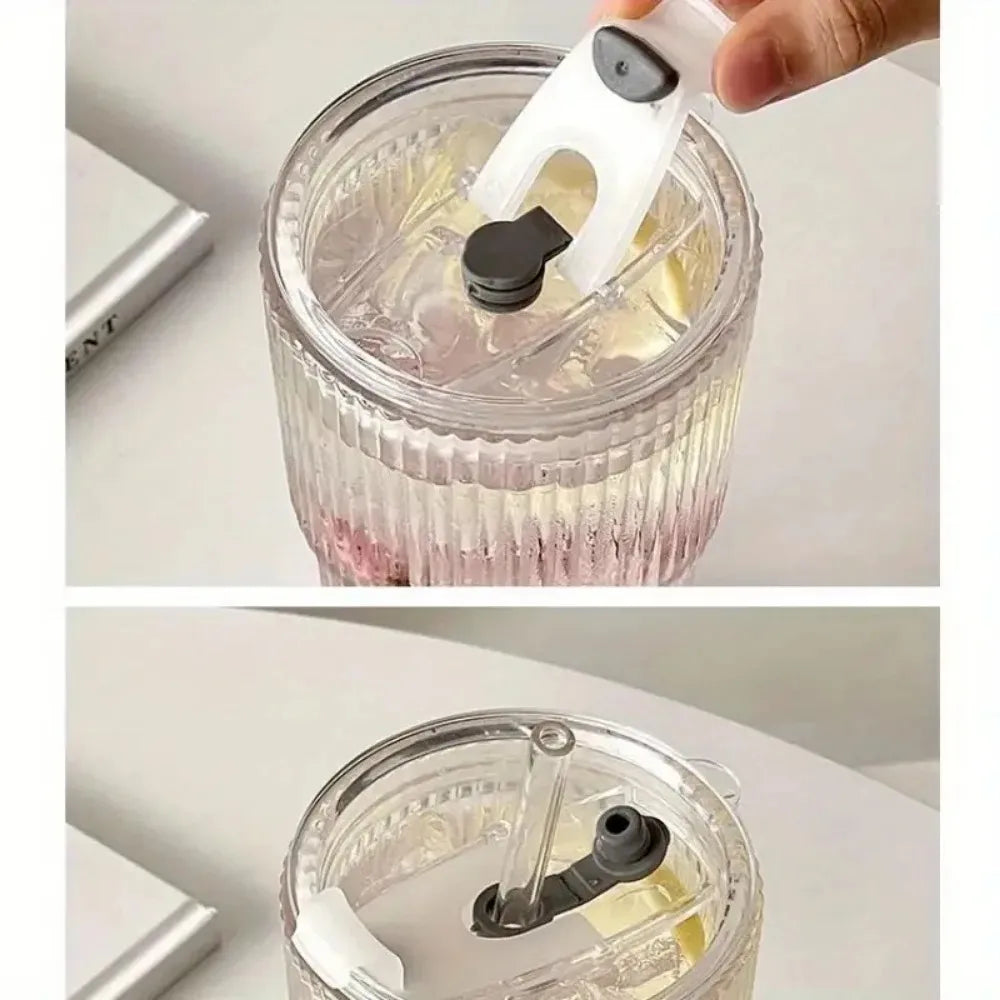 A hand is holding the lid of a 600ml striped glass tumbler with a straw and lid.