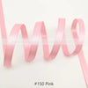 Pink satin ribbon looped and unwound against a white background