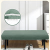 A green stretch jacquard bench cover placed on a wooden bench, with an elastic buckle strap shown nearby.