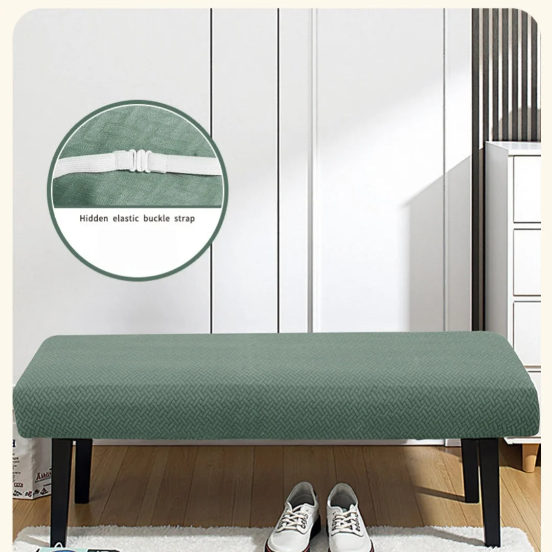 A green stretch jacquard bench cover placed on a wooden bench, with an elastic buckle strap shown nearby.