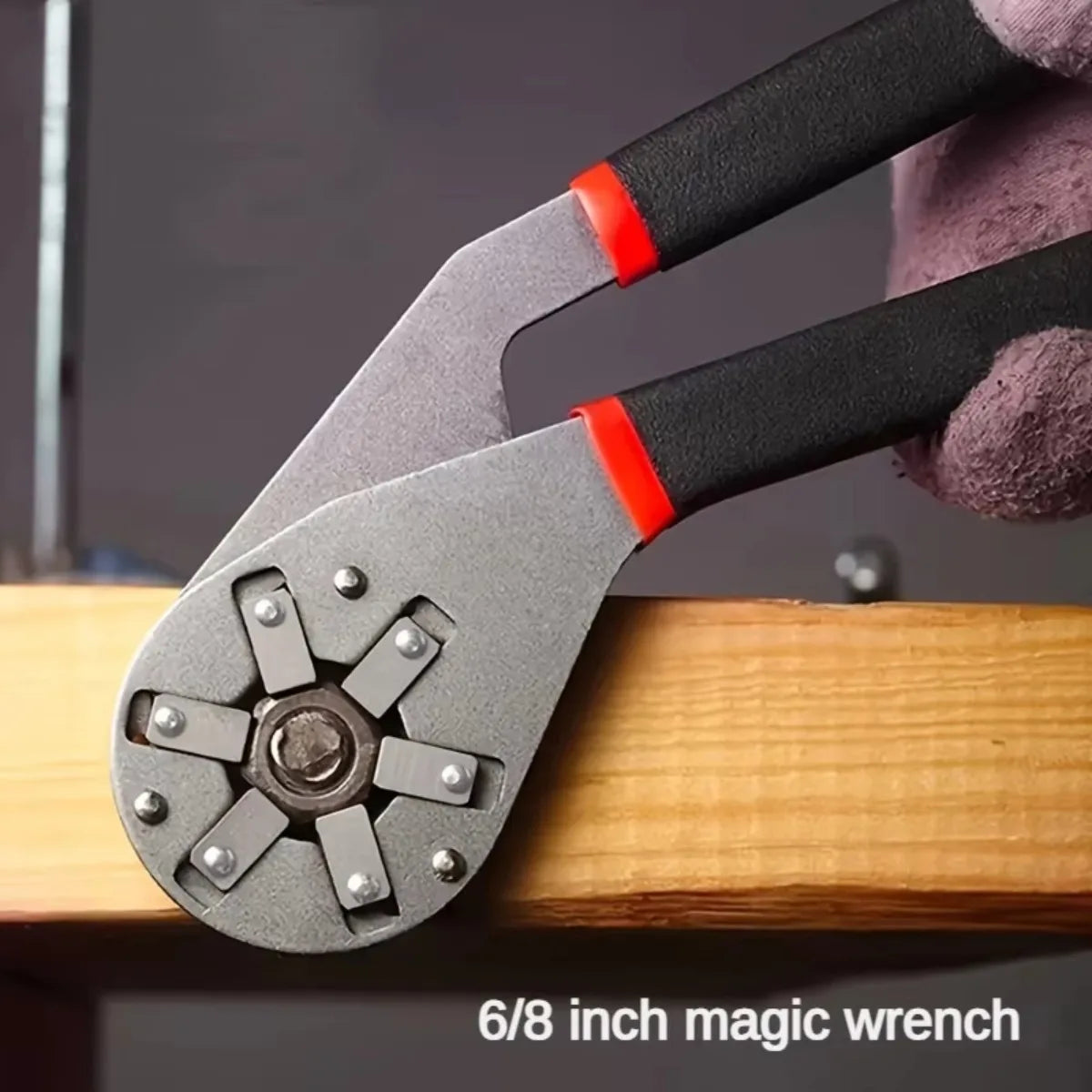 A close-up of a gray 6/8 inch magic wrench with a black and red handle resting on a wooden surface.