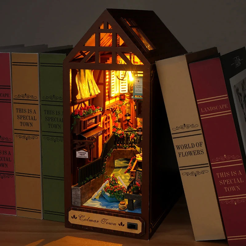 A miniature book nook kit featuring a detailed, illuminated scene of a cozy cottage interior.