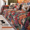 A richly colored floral jacquard sofa blanket featuring deep reds, oranges, and purples with decorative tassels.