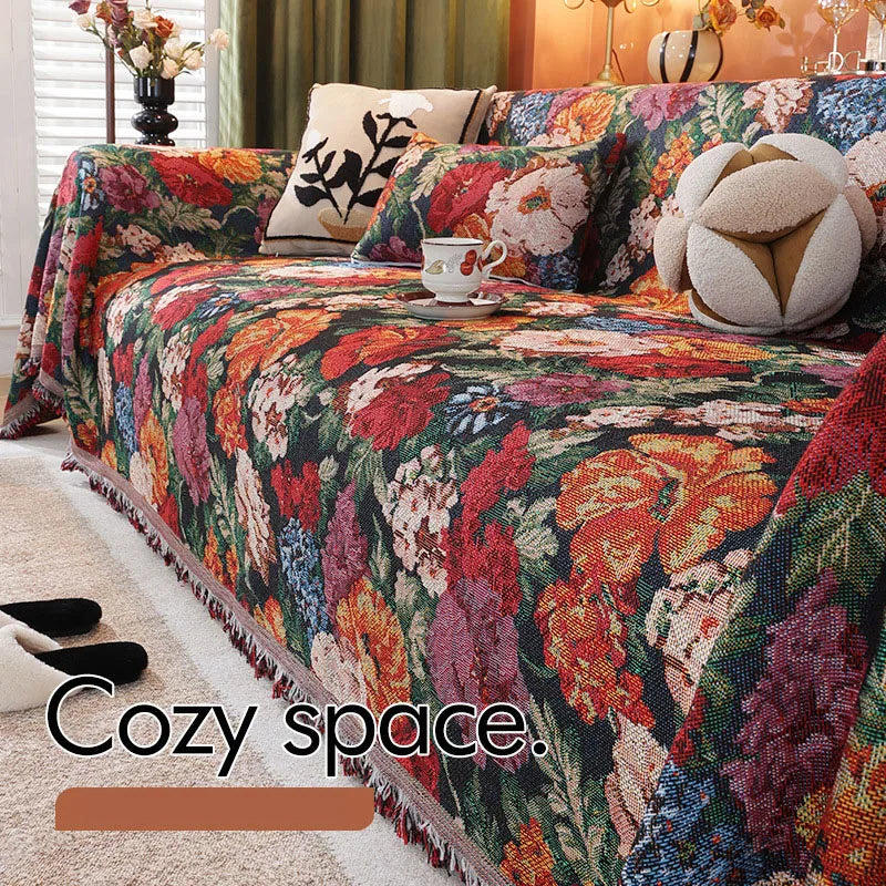 A richly colored floral jacquard sofa blanket featuring deep reds, oranges, and purples with decorative tassels.