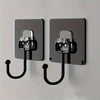 Two modern black adhesive hooks mounted on a silver wall plate for kitchen or bathroom storage