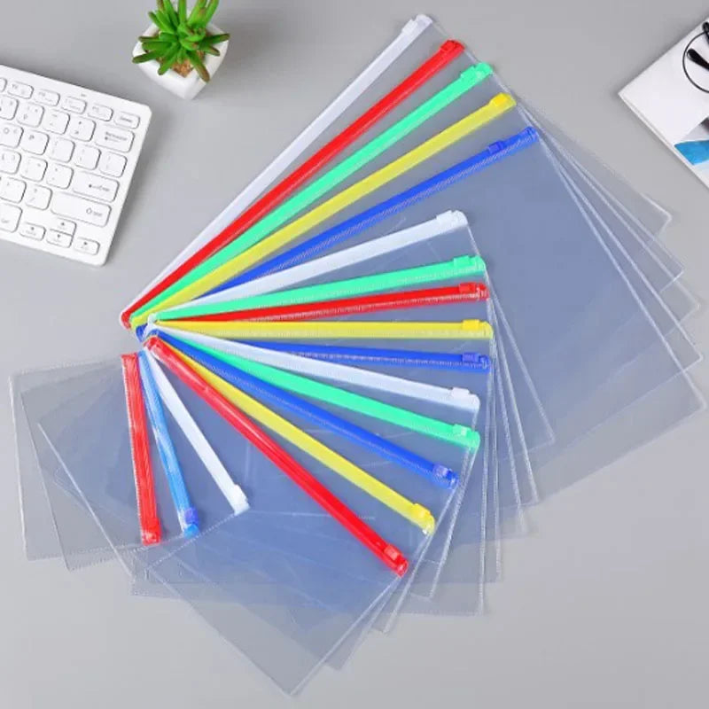 A collection of transparent A4 document organizer pockets with colored dividers arranged diagonally on a gray surface.