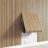 A close-up of wood grain peel-and-stick wall tiles installed vertically on a light-colored wall.