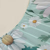 A close-up of a light mint green fitted sheet featuring a white daisy and green leaf floral print.