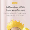 A yellow shampoo cap with a crown design is shown protecting a baby's head from water flow.
