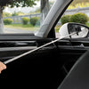 A hand is using a long, clear retractable car mirror and window cleaning wiper to wipe the exterior of a vehicle's side mirro