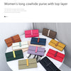 A collection of women's long cowhide leather purses in various colors and shades displayed on a white table.