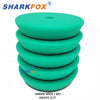 A set of five green heavy cut polishing sponge pads for car detailing and paint correction.