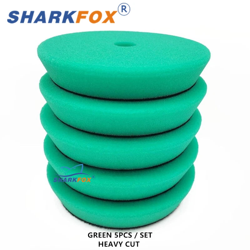 A set of five green heavy cut polishing sponge pads for car detailing and paint correction.