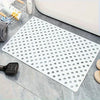 A white anti-slip shower mat with numerous drainage and massage holes is displayed on a gray surface.