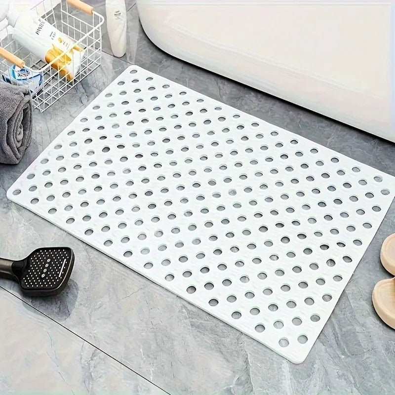 A white anti-slip shower mat with numerous drainage and massage holes is displayed on a gray surface.