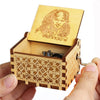 A hand holds an open wooden music box with a carved face on the lid and decorative wood grain.