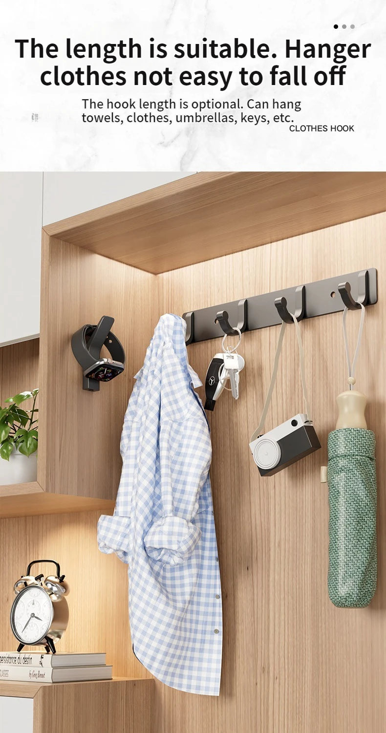 A set of six no-drill aluminum wall hooks with adhesive backing hanging various items like a shirt and a camera in a wooden c