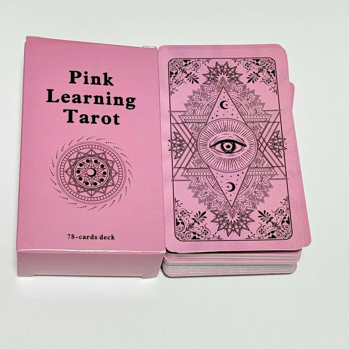 A pink box containing a 78-card deck of Pink Learning Tarot cards featuring intricate designs and an eye symbol.