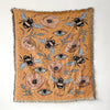 A woven throw blanket featuring a bohemian pattern of bees and floral elements in earthy tones.