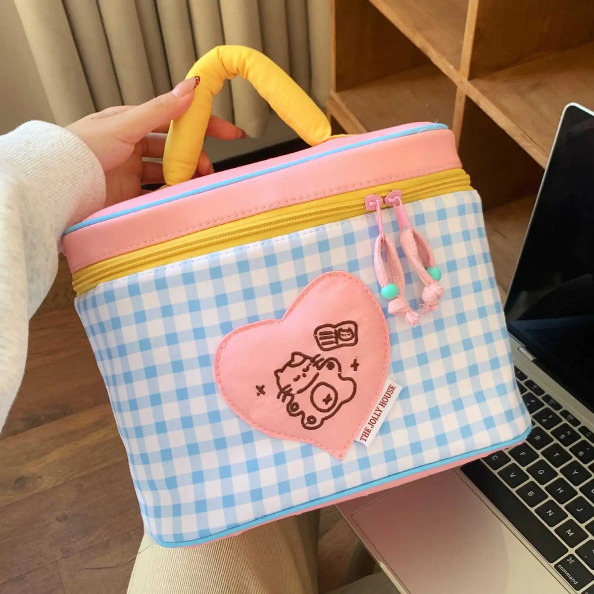 A pink and blue checkered insulated lunch bag with a heart-shaped cartoon design and a yellow handle.