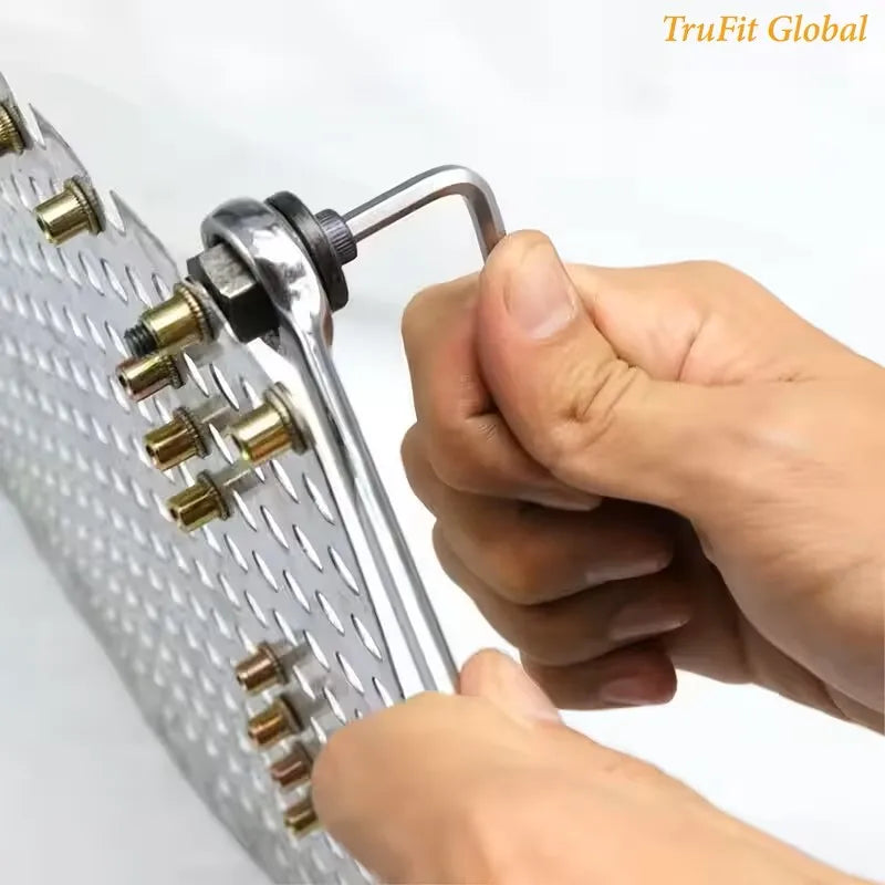 A hand is holding a silver manual rivet nut tool with an interchangeable head, showing the tool's design.
