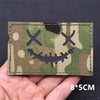A rectangular camouflage tactical patch featuring a skull and crossbones design on a green and brown background.