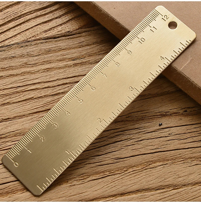 Messlatte in Form eines goldenen Dreiecks diagonal auf einer Holzoberfläche