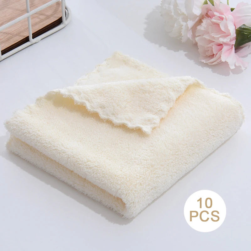 A stack of ten white ultra-soft coral velvet face towels placed on a white surface.
