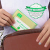 A hand is holding a green disposable toilet seat cover packaged in a brown leather handbag.