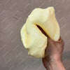 Eine Hand drückt einen großen, blassgelben Stressball-Fidget-Spielzeug.