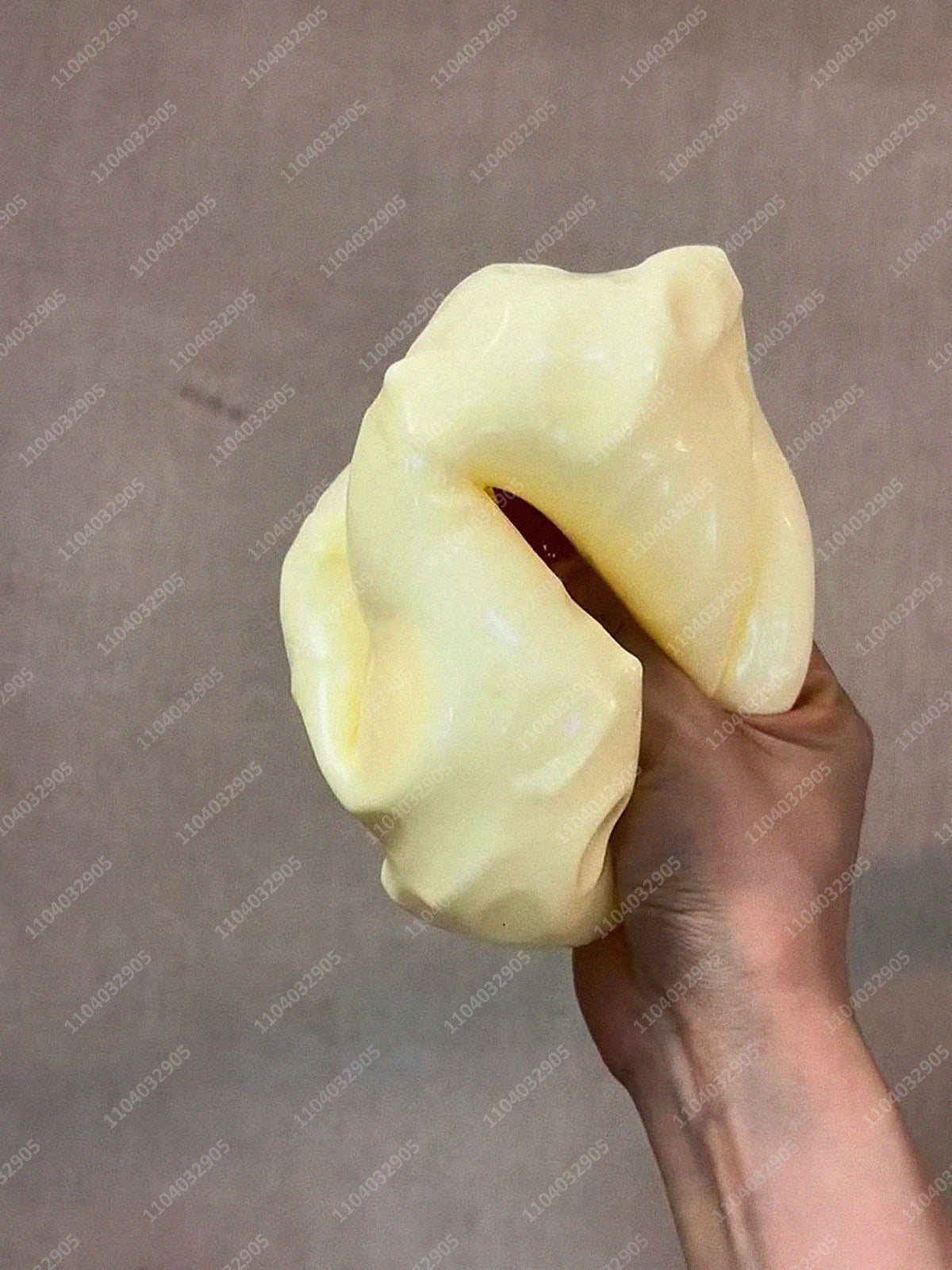 Eine Hand drückt einen großen, blassgelben Stressball-Fidget-Spielzeug.