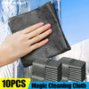 A hand is holding a black microfiber cleaning cloth against a glass surface, demonstrating its use.