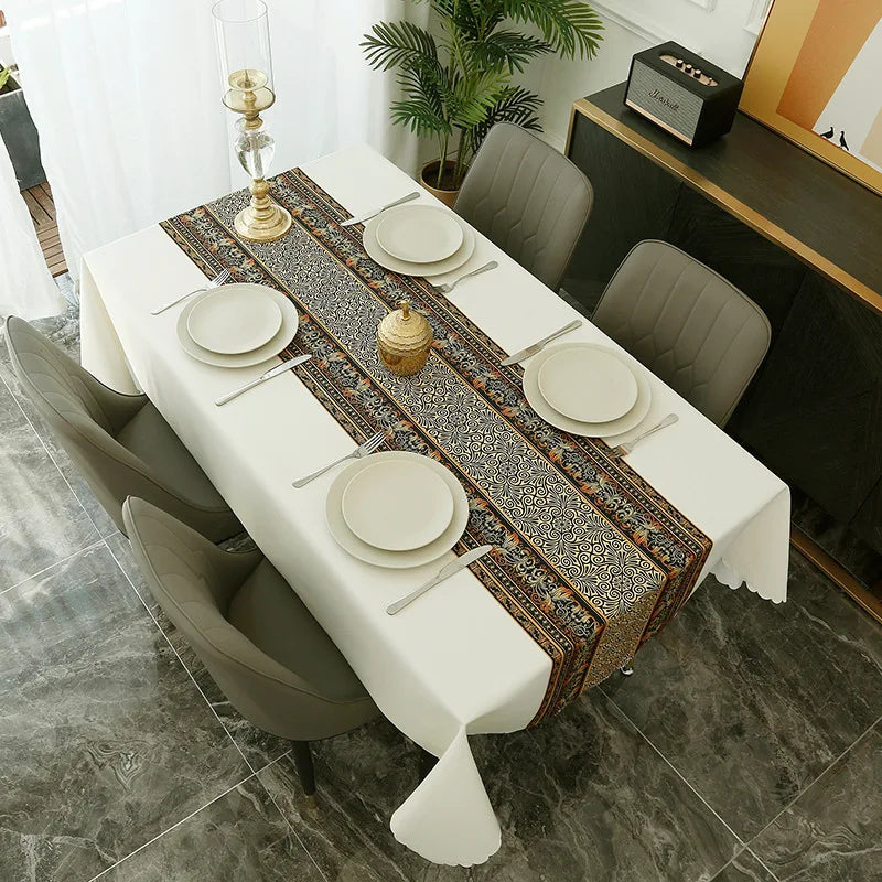 A long white dining table set with placemats and napkins covered by a Nordic geometric waterproof tablecloth.