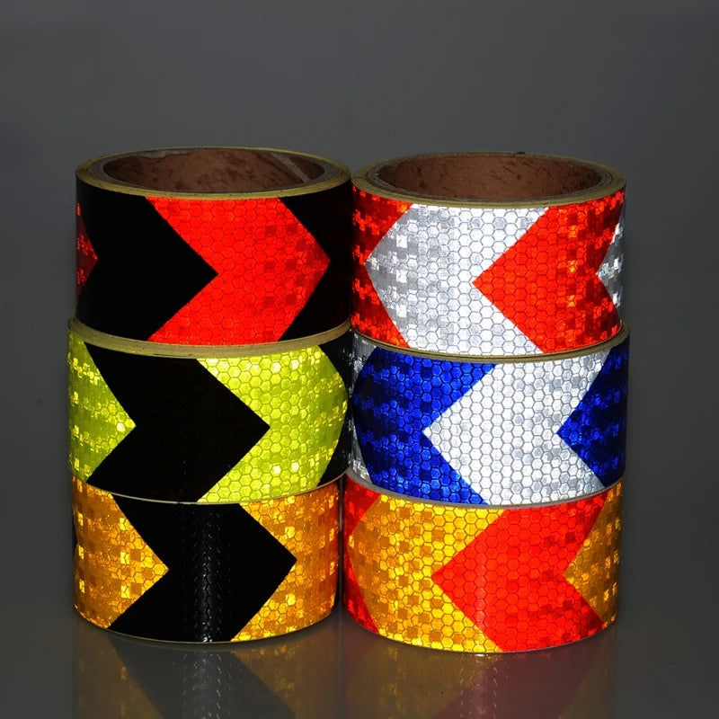 Three rolls of high-visibility reflective safety tape in black, yellow, and red chevron patterns.