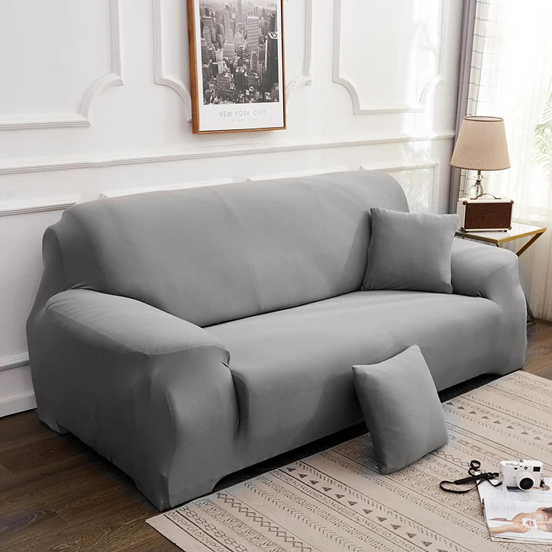 A gray silky soft stretchable sofa cover displayed on a living room sofa.