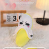 Yellow fruit-shaped plush metronome toy with a sad expression shown in close-up views.