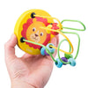 A hand holds a yellow wooden lion bead maze toy with colorful strings and beads.