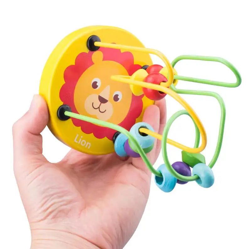 A hand holds a yellow wooden lion bead maze toy with colorful strings and beads.