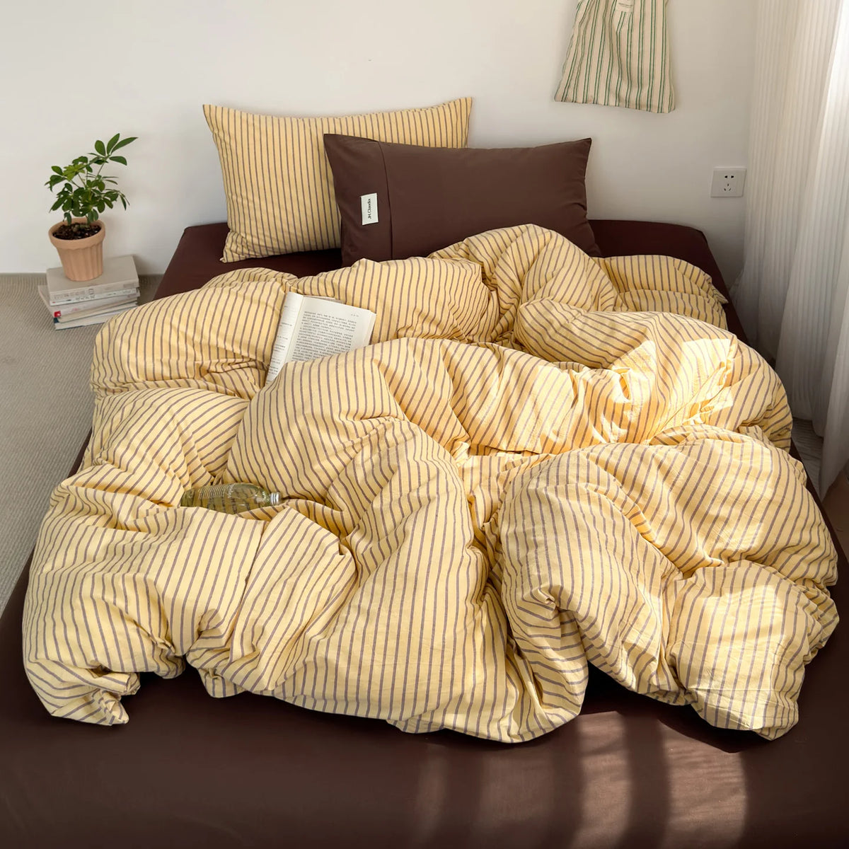 A yellow and beige striped duvet cover set with matching pillows on a brown bed.